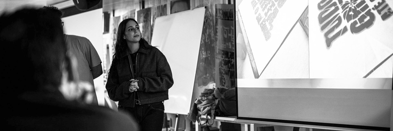 Senhora a apresentar um projeto, com o projetor ao fundo